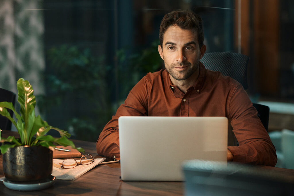 Homem sentando em uma mesa com notebook