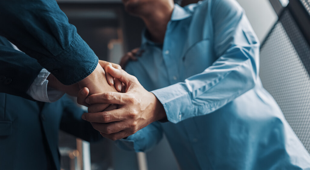 Três homens dando as mãos "fechando um acordo"