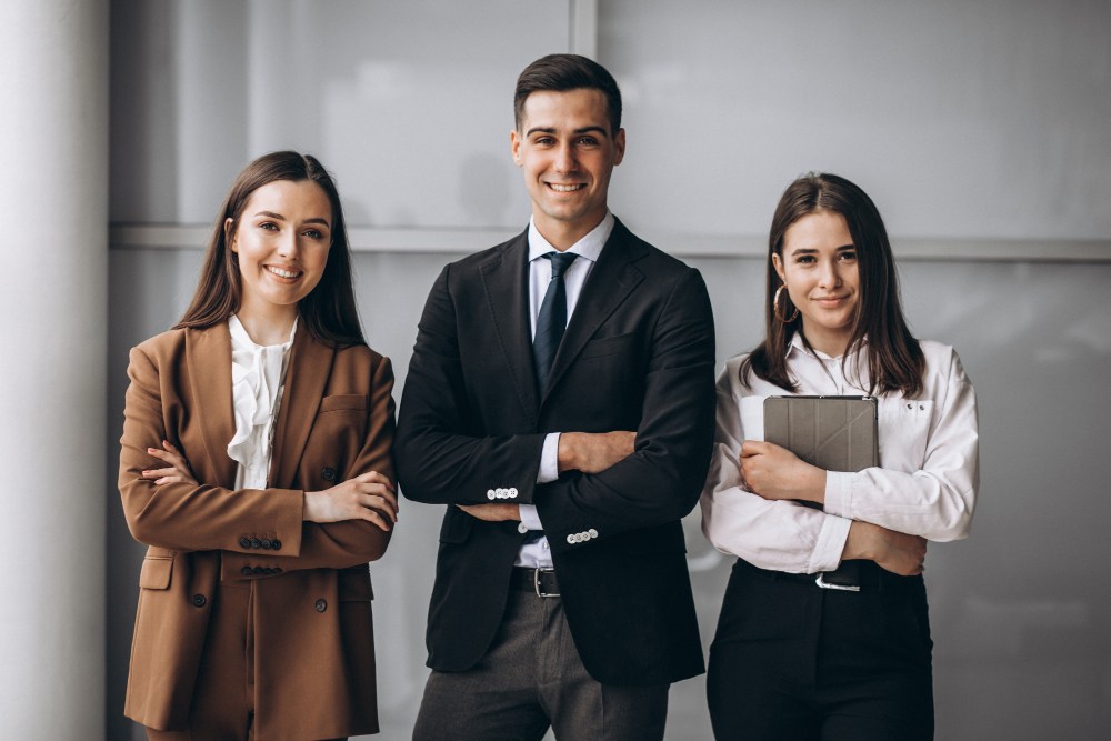 Três advogados de braços cruzados sorrindo para a foto