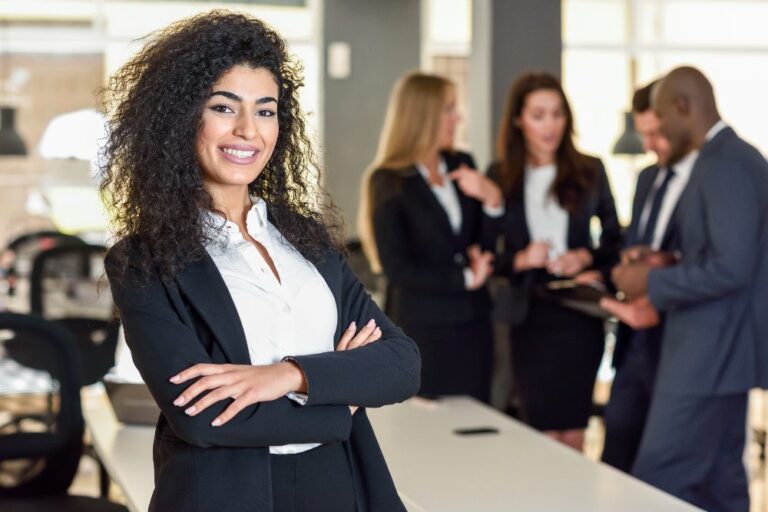 Advogada sorrindo para câmera com advogados atrás